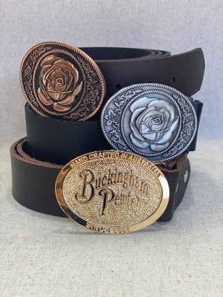 Buckingham Pewter rose belt buckle surrounded by leather belts in various finishes